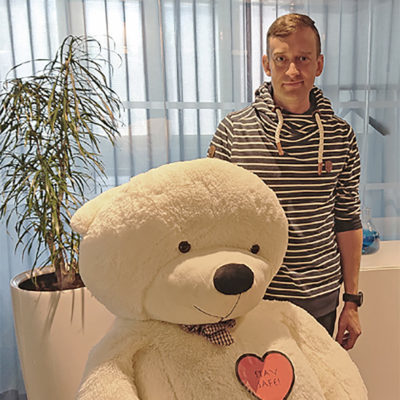 Veritaksen asiakas Joonas Hirn seisoo kuvassa isokokoisen nallepehmolelun kanssa.