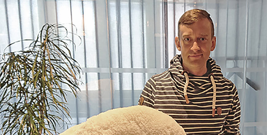 Veritaksen asiakas Joonas Hirn seisoo kuvassa isokokoisen nallepehmolelun kanssa.