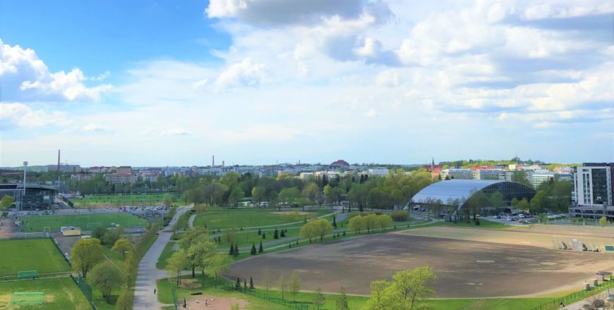 Näkymä Veritaksen pääkonttorista kesäiseen Kupittaanpuistoon, jossa on urheilu- ja jalkapallokenttiä, ulkoilureittejä, jalkapallostadion ja sisäurheiluhalli. Kaukana horisontissa näkyy Turun keskustan rakennuksia.