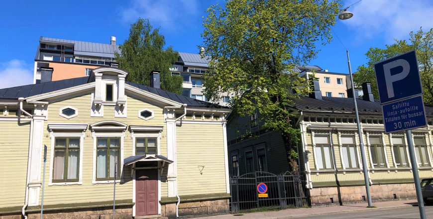 Linnankadun asuintalojen julkisivukuva. Kerrostalo on taka-alalla ja sen edessä vihreät puutalot, joiden välistä on porttikonki sisäpihalle. Talojen edessä on mahdollista pysäköidä.