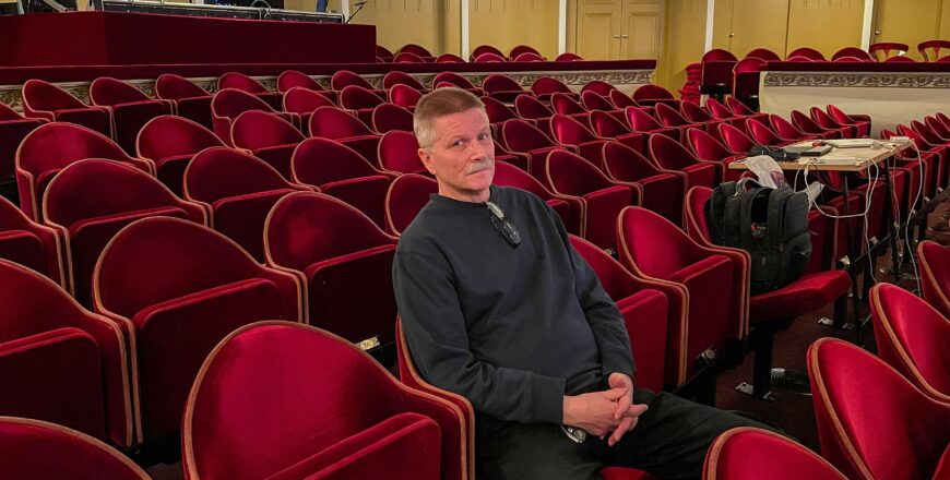 Tom Kumlin istuu yhdellä teatterin punaisista penkeistä.