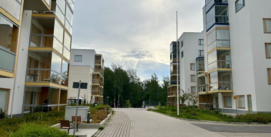 Nuttukujan kiinteistön sisäpiha. Keskellä menee leveä pihatie, jota reunustaa viheralueet. Taustalla näkyy puita.