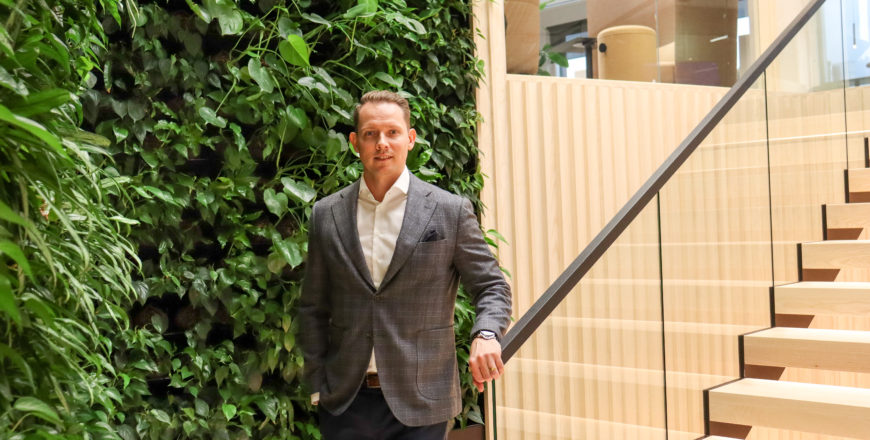 Heikki Palmu seisoo portaikossa yksi käsi kaiteella viherseinän edessä.