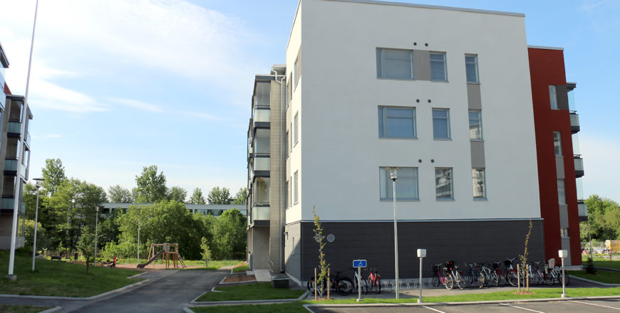 Turun Pryssinkadun kohteen julkisivu sivustapäin. Talo on nelikerroksinen ja valkoinen. Pihalta löytyy parkkipaikkoja ja lasten leikkipaikka.