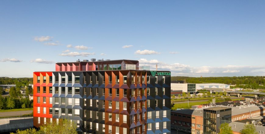 Ilmakuva Veritaksen pääkonttori Trivium Retoriikasta. Kesäinen kuva, jossa etualalla monivärinen Retoriikka. Taustalla sininen taivas, kasvillisuutta sekä lähirakennuksia. Talon takana kulkee Helsingin valtatie.