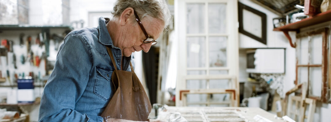Side view of a person scraping window frame on workbench at store workshop
