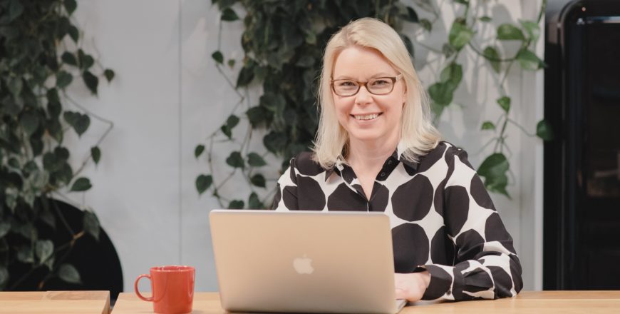 Yrittäjä Tuuli Ilves istuu tietokoneen edessä ja hymyilee kameraan.