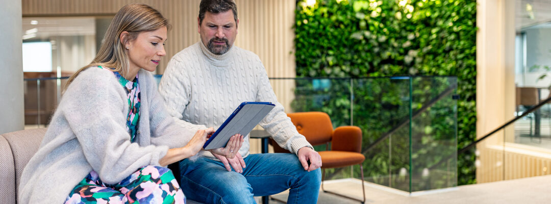 Kaksi henkilöä tutkii tablettia Turun pääkonttorilla.